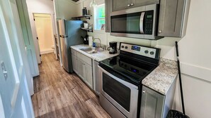 A compact kitchen with stainless steel appliances, a microwave, and a coffee maker.