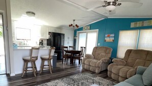 A spacious living room with a patterned rug, a blue accent wall, and a dining area with wooden chairs and a table. - 2 BR 1 BA Dog friendly home in Assateague Pointe WOC: Text BEFORE booking!! (Berlin)