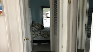 A narrow hallway with a wooden floor leading to a bedroom with a bed and a window. - 2 BR 1 BA Dog friendly home in Assateague Pointe WOC: Text BEFORE booking!! (Berlin)
