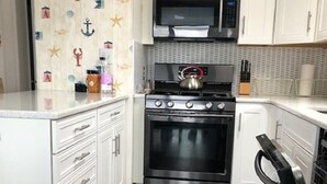 A compact kitchen with white cabinetry, a stainless steel stove, and a microwave. - 2 BR 1 BA Dog friendly home in Assateague Pointe WOC: Text BEFORE booking!! (Berlin)