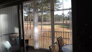 Una stanza con vista su un campo da golf, un divano e un tavolo con sedie.