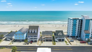A beachfront hotel with multiple buildings, a parking area, and a beach in the background.