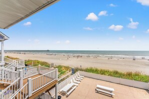 A beach view from a balcony with a wooden deck, white railings, and a clear sky. - Sea Aire II Duplex Up, Pet Friendly, Oceanfront, Shared Game Room (North Myrtle Beach)