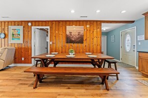 A dining area with a wooden table and benches, a clock, and a framed picture on the wall. - Sea Aire II Duplex Up, Pet Friendly, Oceanfront, Shared Game Room (North Myrtle Beach)