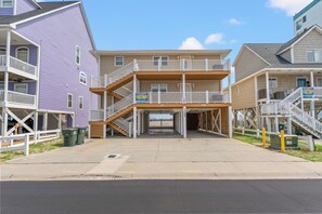 A multi-story building with a central entrance, balconies, and a covered parking area. - Sea Aire II Duplex Up, Pet Friendly, Oceanfront, Shared Game Room (North Myrtle Beach)