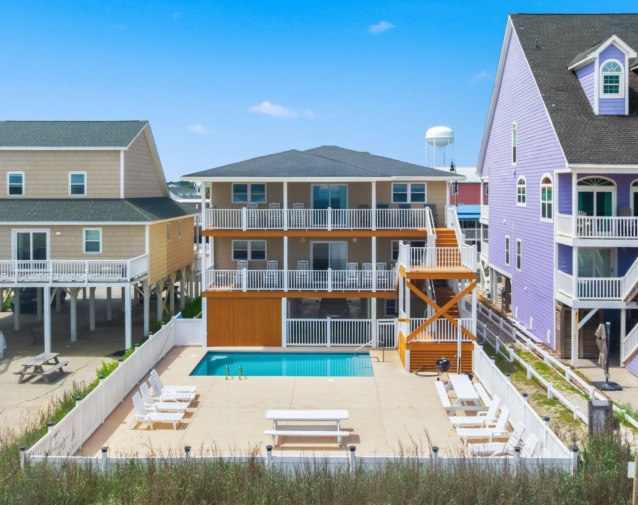 A beachfront property with a swimming pool, multiple balconies, and a covered deck area.