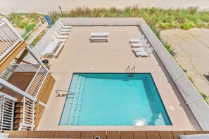 A rectangular pool with a wooden deck surrounding it, a white fence, and a beach in the background. - Sea Aire II Duplex Up, Pet Friendly, Oceanfront, Shared Game Room (North Myrtle Beach)