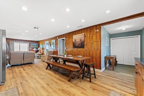 A spacious room with a wooden dining table, benches, and a sofa. - Sea Aire II Duplex Up, Pet Friendly, Oceanfront, Shared Game Room (North Myrtle Beach)