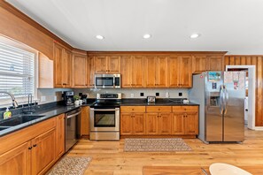 A modern kitchen with wooden cabinets, stainless steel appliances, and a black countertop. - Sea Aire II Duplex Up, Pet Friendly, Oceanfront, Shared Game Room (North Myrtle Beach)