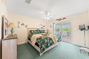 A bedroom with a bed, a ceiling fan, a window, and a view of the outdoors. - Uptown Girl - 4 Bed/4 Bath House a Block from the Beach with Oceanview Balcony, Walk to Pier (North Myrtle Beach)
