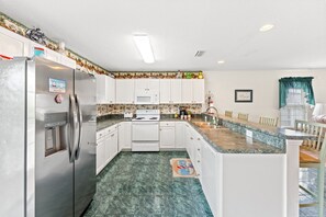 A kitchen with white cabinets, a stainless steel refrigerator, a microwave, and a stove.
