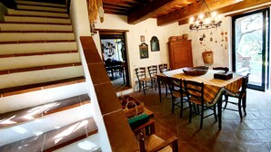 Un comedor con una mesa y sillas de madera, un candelabro y una escalera que lleva a otra habitación.