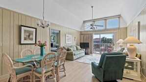 A spacious living area with a dining table, chairs, a sofa, and a TV.
