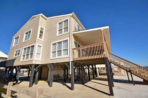 A two-story house with a wooden deck and a covered area.