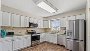 Una cocina moderna con armarios blancos, electrodomésticos de acero inoxidable y piso de madera.
