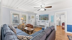 A living room with a sofa, a coffee table, a desk, and a ceiling fan. - Summer Fun - Beach Across the Street (North Myrtle Beach)