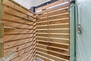 Una habitación con listones de madera en las paredes, un tubo de metal y un techo blanco.