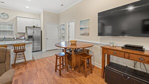 Una cocina moderna con un refrigerador de acero inoxidable, una mesa de comedor de madera y taburetes de bar.