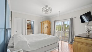 Un dormitorio con cama, armario de madera, televisor y balcón con vistas.