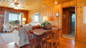 A wooden cabin with a dining area, a sofa, and a view of the outdoors. - Summer Rates Reduced at Magnificent Surf (North Myrtle Beach)