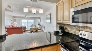 A kitchen with granite countertops, wooden cabinets, a built-in oven, and a dining area with a red sofa and table.