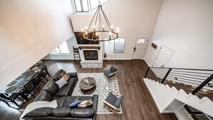Un amplio espacio de sala con chimenea, una mesa de comedor con sillas, un sofá y una escalera.