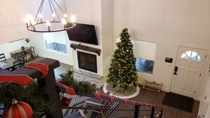 Amplia sala de estar con chimenea, un árbol de Navidad y un comedor con vistas al exterior.
