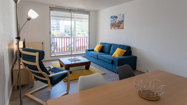 A modern living room with a blue sofa, a wooden coffee table, a blue armchair, and a floor lamp. - T3 3* apartment in the heart of Anglet, a few minutes from the beaches (Anglet)