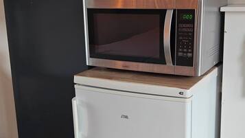 Una kitchenette compacta con un microondas encima de un refrigerador pequeño.