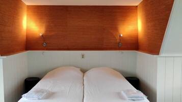 A bedroom with a wooden ceiling, two bedside tables, and a bed with white linens.