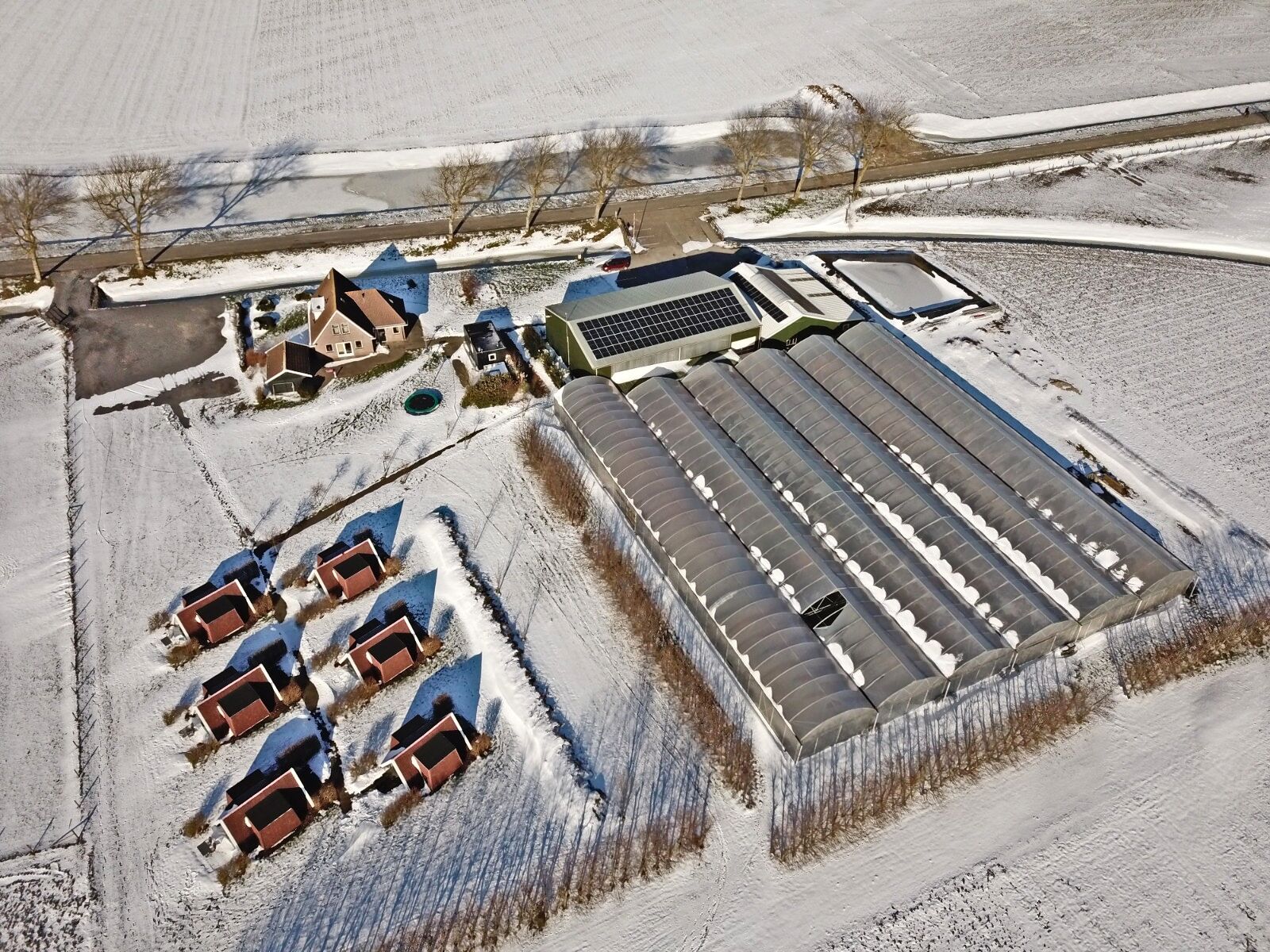 Eine Vogelperspektive einer großen Industrieanlage mit mehreren Gebäuden, darunter ein großes Lagerhaus und kleinere Bauten.
