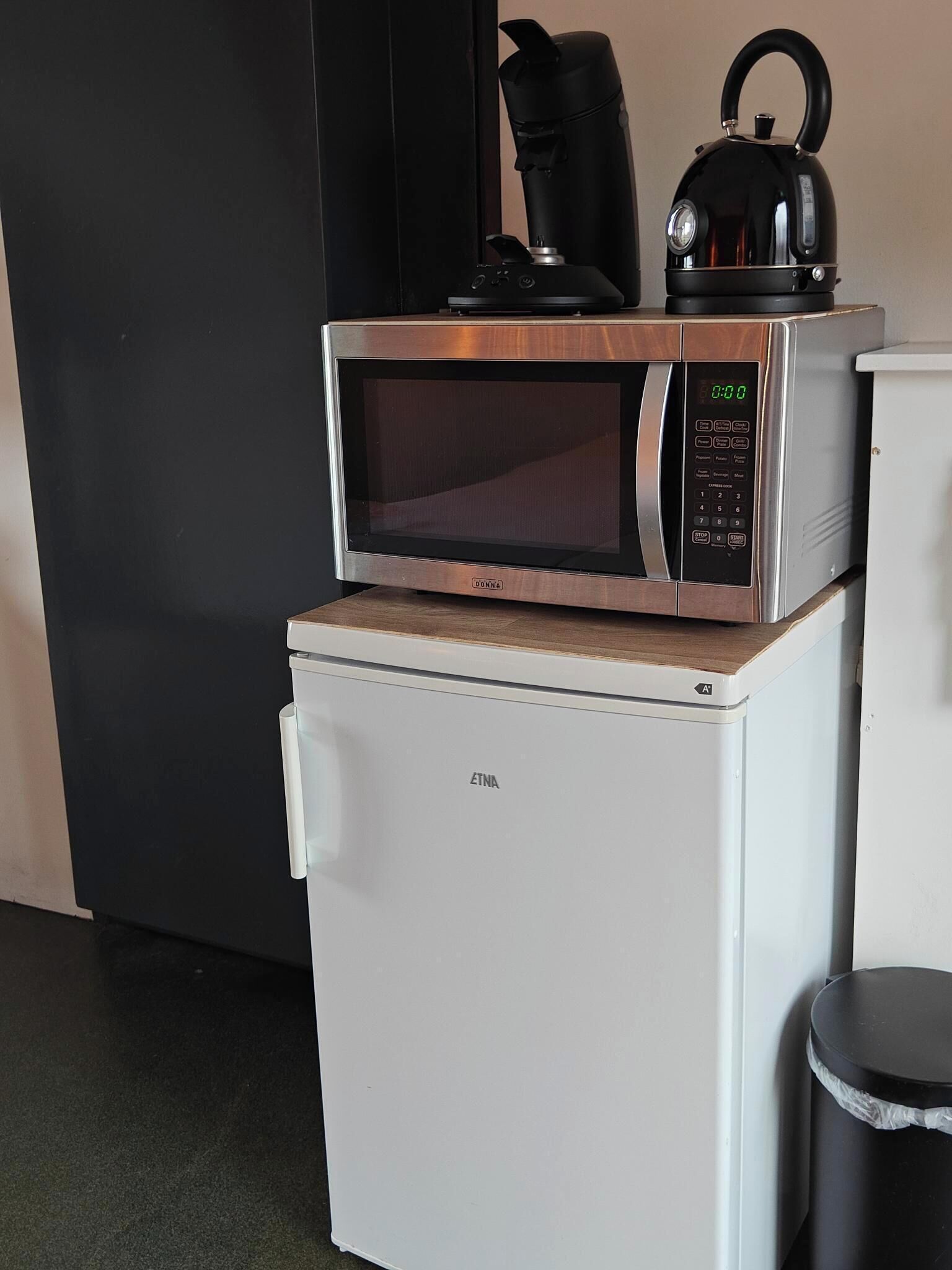 A compact kitchenette with a microwave oven on top of a small refrigerator.