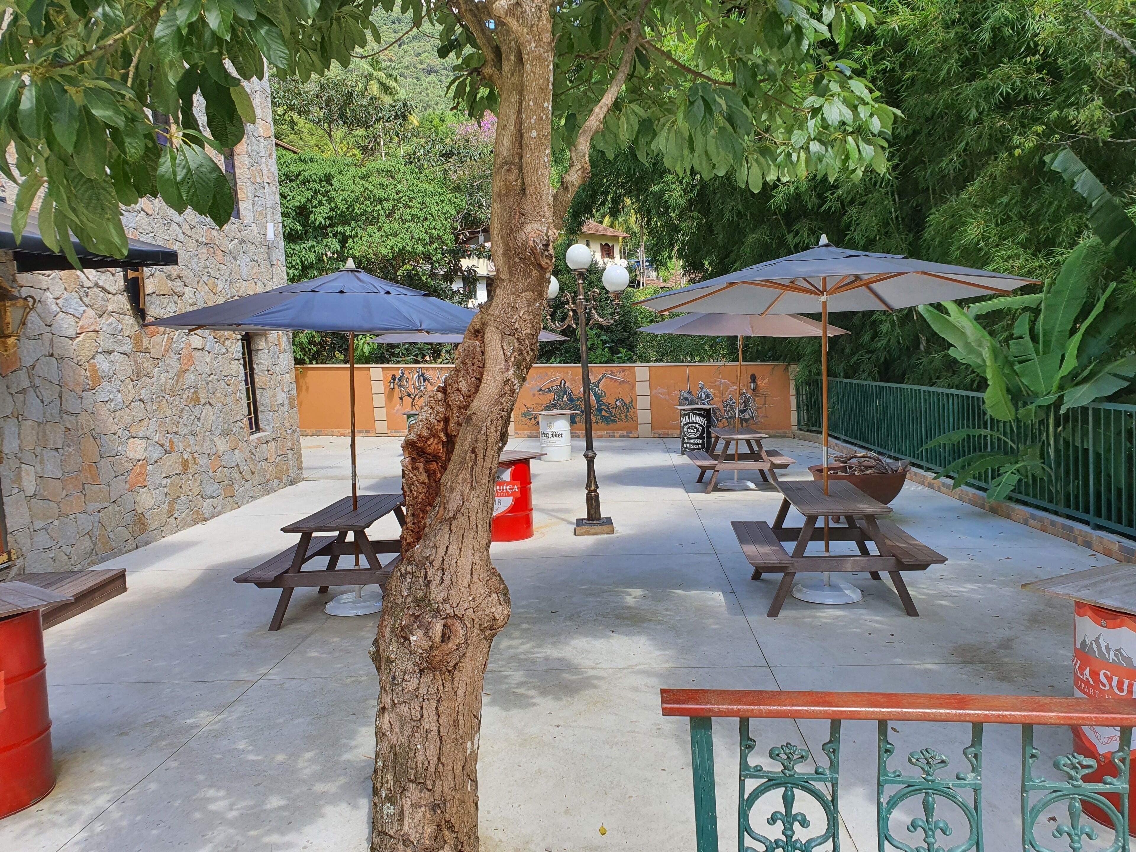 An outdoor patio with stone walls, picnic tables, and umbrellas.