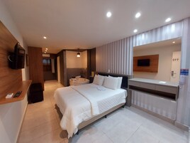 Una habitación de hotel moderna con una cama grande, un escritorio empotrado, un televisor de pantalla plana y un baño independiente con bañera.