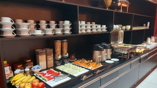 A buffet with various food items and utensils, including fruits, vegetables, and condiments. - Hotel Vila Suíça 1818 (Nova Friburgo)