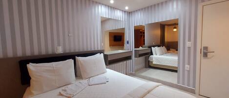 Une chambre d’hôtel avec un grand lit, une table de chevet, un miroir et une armoire.