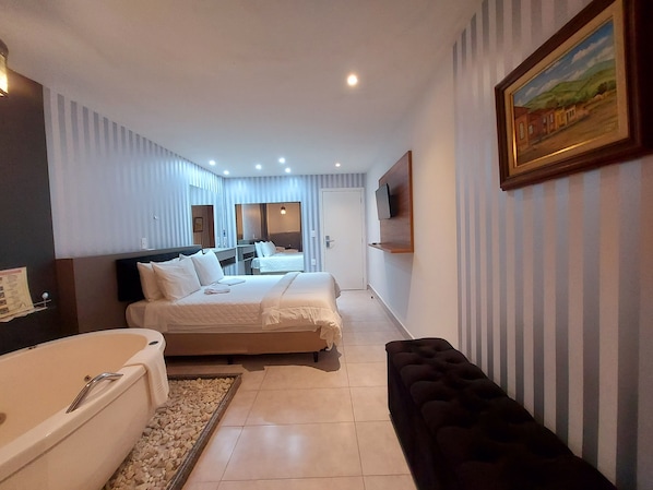 A hotel room with two beds, a large mirror, a TV mounted on the wall, and a painting.