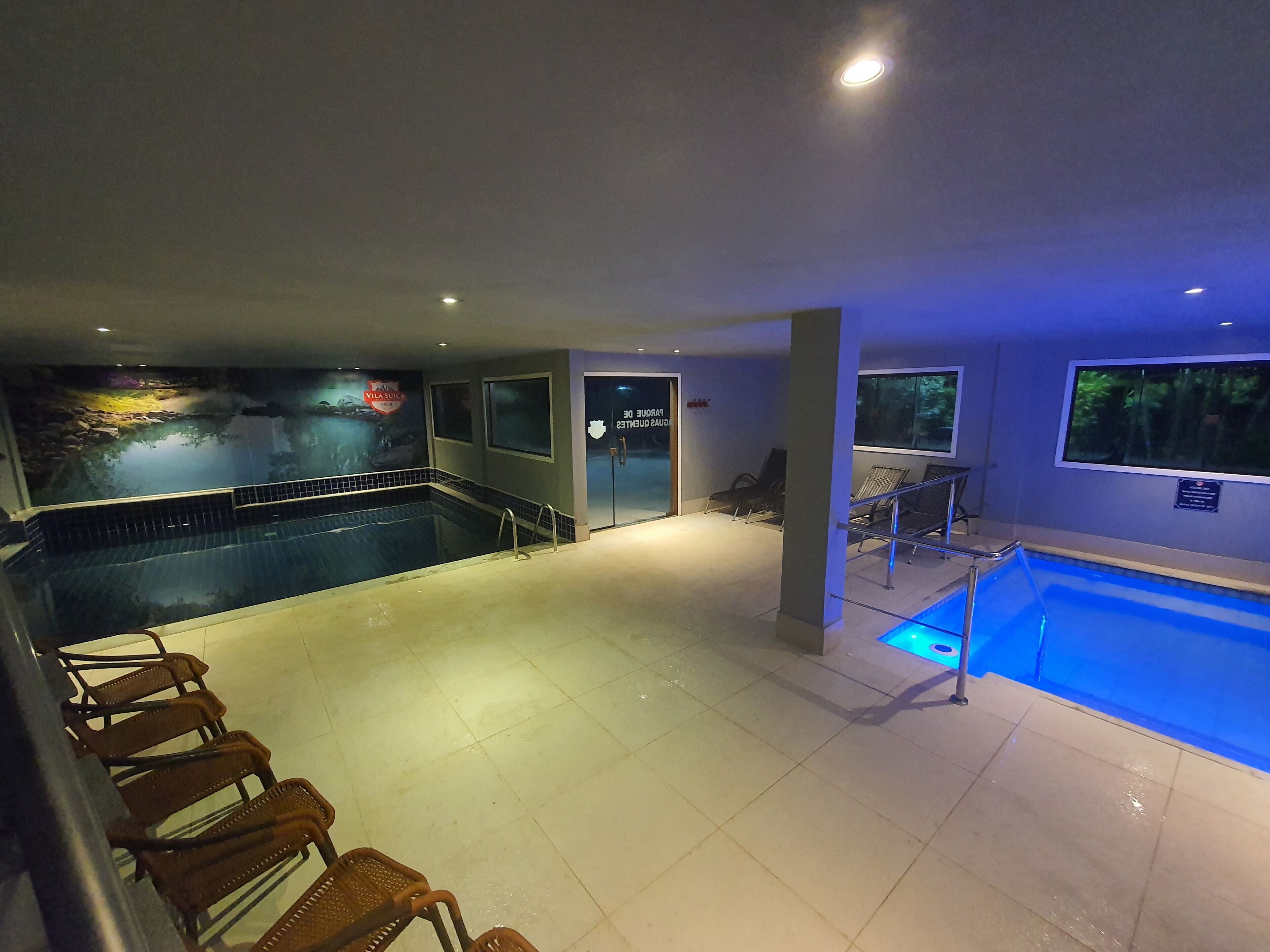 An indoor swimming pool with a mural, lounge chairs, and a door labeled "Lounge Area".