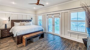 A bedroom with a large bed, wooden floor, ceiling fan, and large windows with blinds. - Spacious Family and Pet Friendly 30A Home • Walk to Beach, Shops, & Dining (Santa Rosa Beach - Gulf Place 30A)