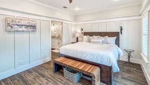 A bedroom with a wooden headboard, a large bed with white bedding, a ceiling fan, and a wall-mounted light fixture. - Spacious Family and Pet Friendly 30A Home • Walk to Beach, Shops, & Dining (Santa Rosa Beach - Gulf Place 30A)