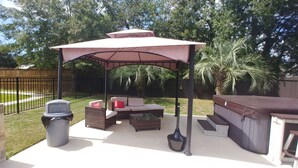 An outdoor patio with a covered seating area, a grill, and a hot tub. - Beaujolais Villas (D'Iberville)