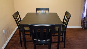 A dining table with four chairs, carpeted floor, and beige walls. - Beaujolais Villas (D'Iberville)