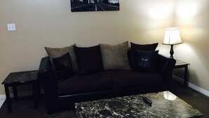 A living room with a dark brown sofa, a marble coffee table, a lamp, and a framed picture on the wall. - Beaujolais Villas (D'Iberville)