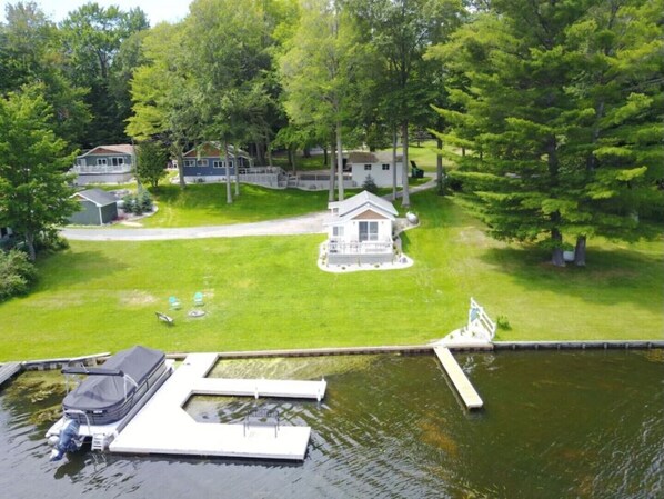 A lakeside property with a dock, a small house, and a well-maintained lawn.