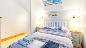 A bedroom with a skylight, a bed with striped bedding, two bedside tables with lamps, and a framed picture on the wall. - 1 bedroom accommodation in Ulva Ferry (Ulva Ferry)