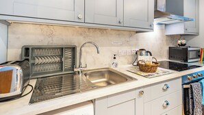 A kitchen with grey cabinets, a stainless steel sink, a toaster, a kettle, and a microwave. - 1 bedroom accommodation in Ulva Ferry (Ulva Ferry)