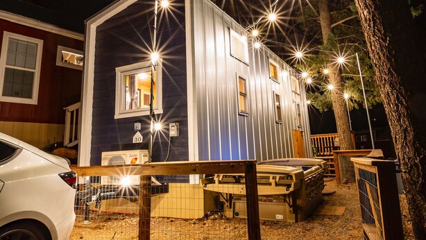 A mobile home with a fenced yard, a picnic table, and a car parked nearby. - Boutique Tiny Home! Pikes Peak Views, HOT TUB, fire pit, & cozy vibes. (Woodland Park)