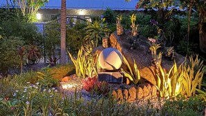 A landscaped garden with a variety of plants and a large spherical stone centerpiece. - Cabanes des Anges Guest House (La Digue)