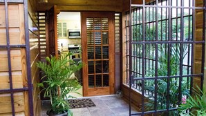 A wooden exterior with a welcome mat, potted plants, and a view into the interior. -   Luxury Log Cabin with picturesque Mountain view (Kingston)