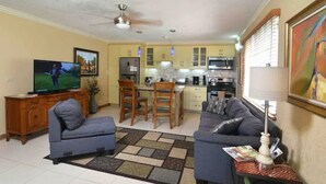 A living room with a sofa, TV, and a dining area with chairs and a table. -   Luxury Log Cabin with picturesque Mountain view (Kingston)